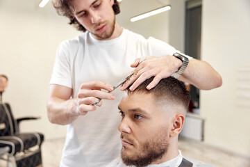 hairdresser does haircut for man using comb and grooming scissors