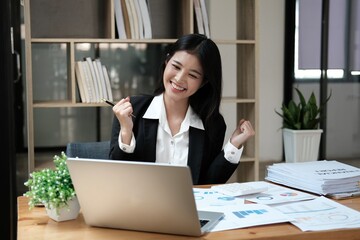 Asian businesswoman raising hands happily with successful plan with happy smile with laptop...