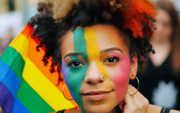Colored woman with her face painted in LGBT Pride rainbow colors and a flag in the background. Close up portrait. Shallow field of view. Illustrative Generative AI. Not a real person.