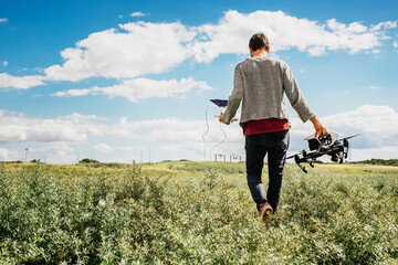 Man walking in field carrying drone