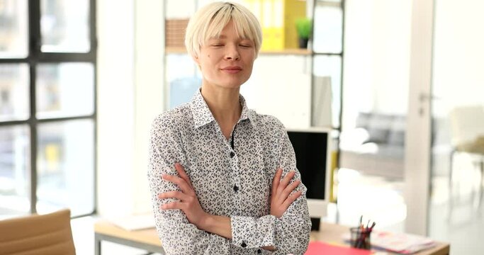 Blonde confident woman crosses arms in office slow motion