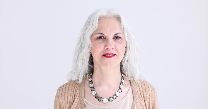 Elegant mature woman with grey hair and necklace in studio