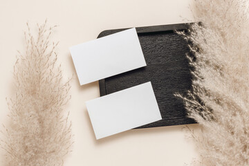Minimal business paper sheet cards on wooden stand with pampas fluffy grass. Aesthetic paper mockup...
