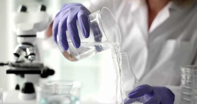 Laboratory worker pours water into flask for investigation