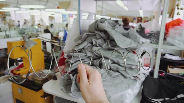 Woman hand holds metal spring in parachute sewing workshop