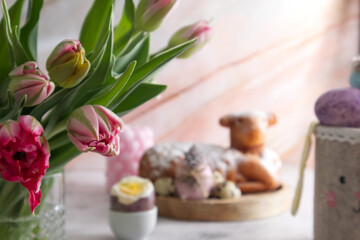 Fototapeta na wymiar Bouquet of pink tulips on the table against the background of Easter cake and Easter eggs