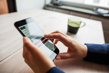 Woman sitting at wooden table and using smart phone