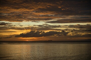 Picturesque sunset on the beach of Siquijor in the Philippines, the whole sky glows in golden yellow color.