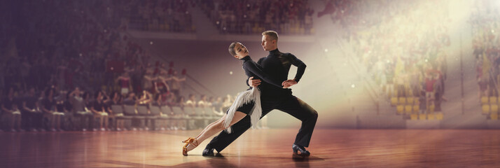 Passionate performance. Young dancers in beautiful stage costumes dancing tango at stage under...
