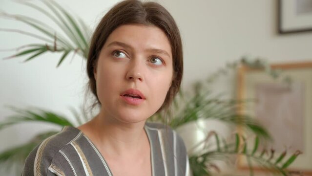 Close up shot of  woman turning her face to side. Young woman looking away in thought, thinking and listening to somebody sitting indoors. Charming female portrait.