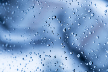 natural water drops on the window glass. blue background with rain on the window, close-up
