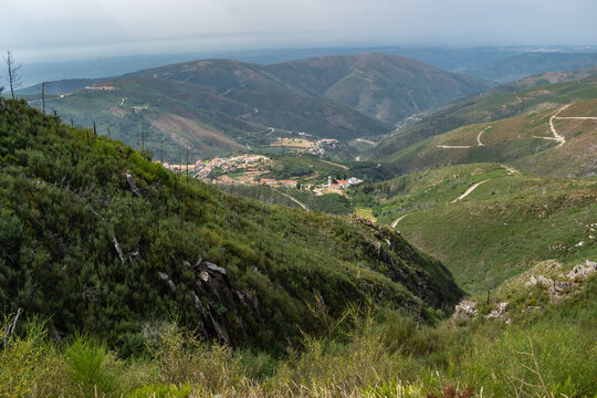 Green bushes on a hill, viewpoint with an aerial view of the village in the background and gradient mountains on the horizon, Arganil PORTUGAL
