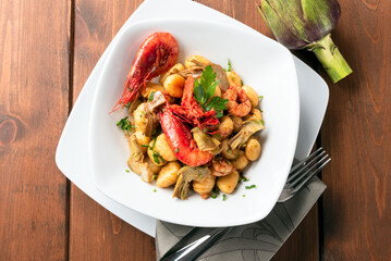 Gnocchi di patate conditi con carciofi e gamberi, cibo italiano 