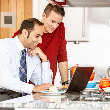 Gay Lifestyle: Modern Communication. A same sex, mixed race couple using a laptop computer together over breakfast. From a series of related images.