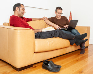 Gay Lifestyle: Relaxing at Home. A same sex, mixed race male couple rest and put their feet up after a busy day. From a series of related images.