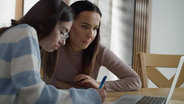 Caucasian mother helping her teenage daughter in doing homework at home. Shot with RED helium camera in 8K.  