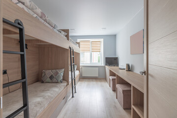 Hostel dormitory beds arranged in dorm room with white plain bunk bed in dormitory.Hostel dormitory have many beds arranged in one room. Clean hostel small room with wooden bunk beds. small hotel