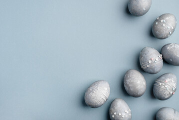 Festive Easter background. Gray-blue Easter eggs with stars on a blue table. Banner with a place for text. Top view.
