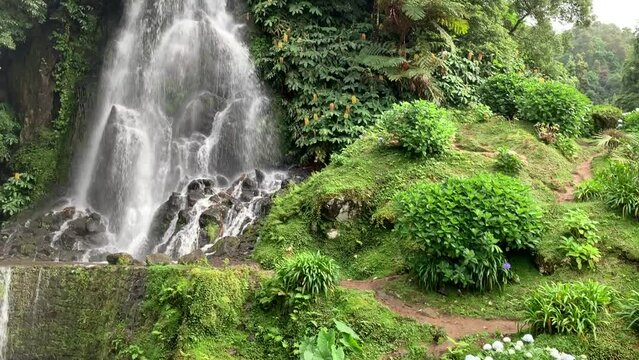 Waterfall of Ribeira dos Caldeiroes with orchid and ginger lily flowers, Sao Miguel, Azores, Portugal, Atlantic