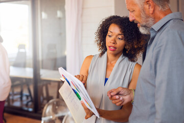 Man and woman analyzing charts in office