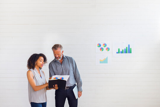 Man and woman analyzing charts in office