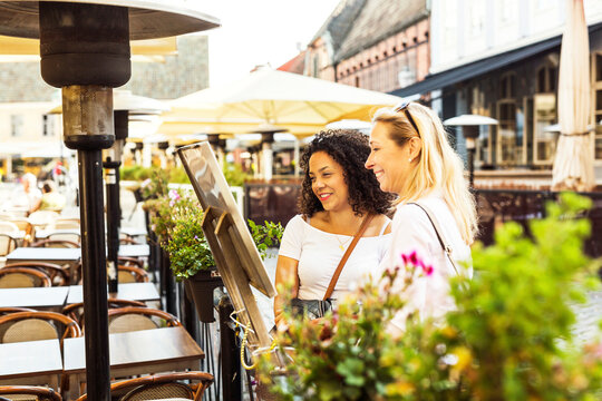 Two women reading menu by sidewalk cafe