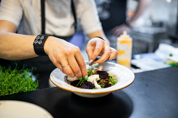 professional chef's hands cooking beetroot salad with feta cheese in a restaurant kitchen