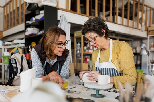 Two women making pottery in workshop