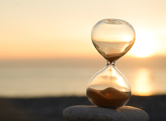 Hourglass on the beach, on the Black sea coast. Hourglass close up in a warm golden morning...