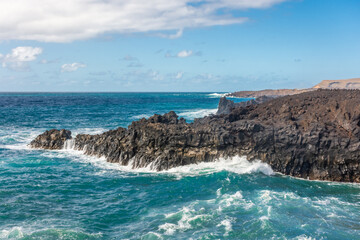 Obraz premium Powerful waves of the Atlantic Ocean crashing on the volcanic cliffs of Los Hervideros in Lanzarote, Canary Islands, Spain