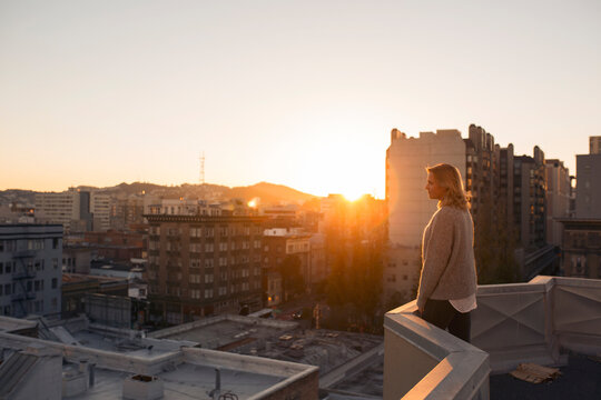 Woman standing on terrace at sunset