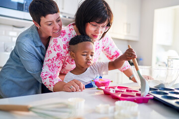 Lesbian couple and son baking heart-shape cupcakes in kitchen