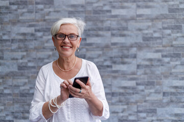 Senior businesswoman with short hair standing against wall