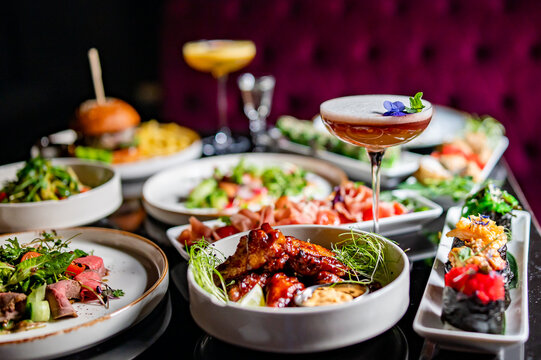 cocktail glass on table full of delicious food in plates in restaurant