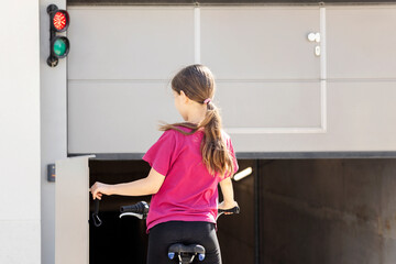 Garage Gate Door of Underground Parking in Residential Building. Girl Cyclist Opening Automatic...