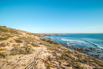 Breathtaking cliffs with pebble beach in the afternoon sun on the Atlantic coast at Vila Nova de Milfontes, Odemira, Portugal. In the footsteps of Rota Vicentina. Fisherman trail