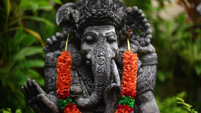 Old statue of Ganesha in garden with decorations