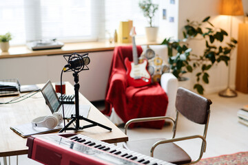 Modern recording studio with synthesizer and microphone on table