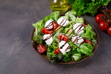 Salad with mozzarella cheese, lettuce, cucumber and tomatoes with spices and olive oil topped with...