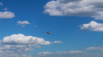 Naklejka na ściany i meble Helicopter in blue cloudy sky 