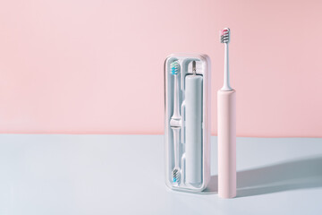 Electric toothbrush in special container against blue-pink background.