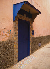 Blue door of a residential building in the streets of the Medina of Marrakech, Morocco, with a bike next to it