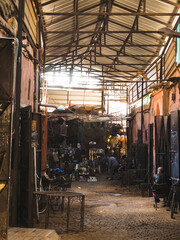 Busy Souk market alley selling and welding metal wares in the heart of the Medina of Marrakech, Morocco, dark street with sunlight