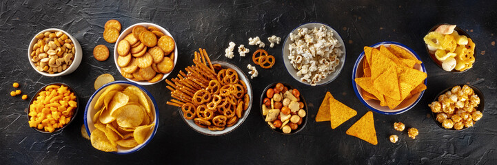 Salty snacks, party mix, overhead flat lay panorama. An assortment of appetizers. Potato and...