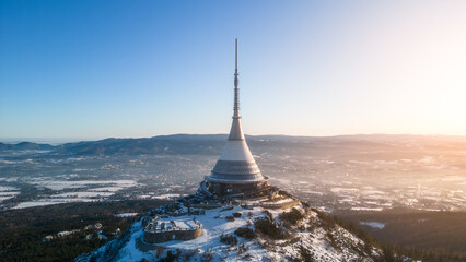 Jested mountain with modern hotel and TV transmitter on the top, Liberec, Czech Republic. Sunny winter day with snowy landscape. Aerial view from drone.