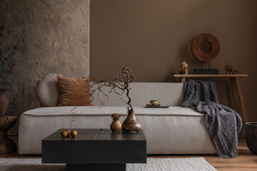 Wabi sabi living room interior with modular sofa, stylish vase with branch, square coffee table, blue plaid, brown pillows, wooden sculpture and personal accessories. Home decor. Template.