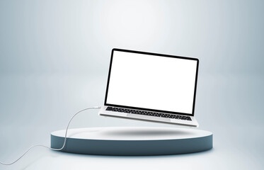 Laptop with cable floating on colored pedestal and blue background,