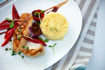 Grilled chicken fillet and vegetables. Bulgur porridge. Couscous on a white plate. Useful healthy food. Roasted peppers, onions, greens and microgreens. Meat and vegetable top view background.