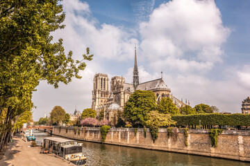 Notre Dame cathedral with houseboats on Seine during spring time in Paris, France