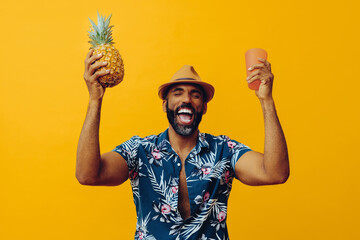 cheerful man wearing Hawaiian shirt and hat. Holding pineapple and pink cup - obrazy, fototapety, plakaty